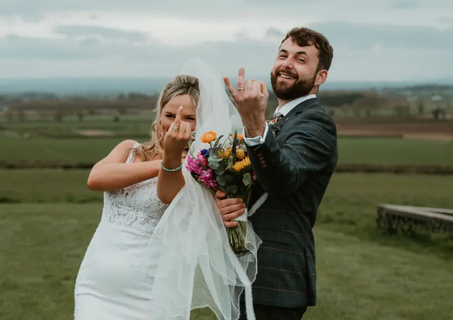 Hannah and Jake raising their hands together against the open fields