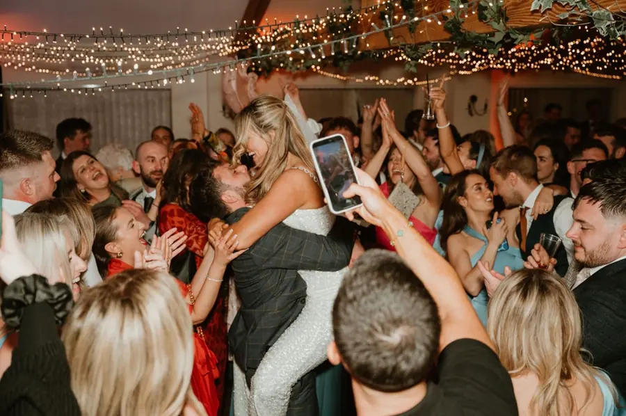 Guests holding phones around Hannah and Jake on the evening dance floor