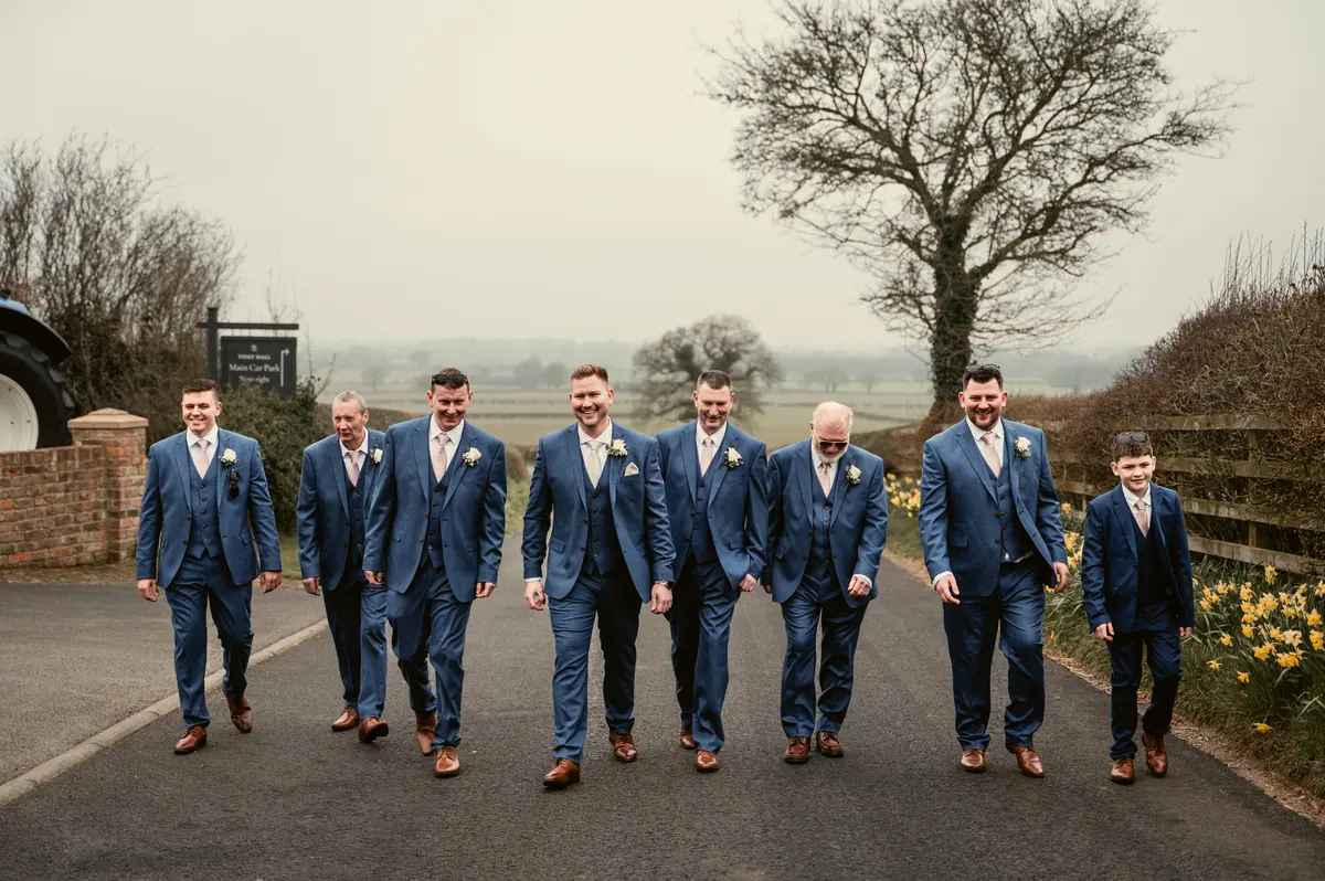 Jayrrd walking outdoors with eight men in matching blue suits