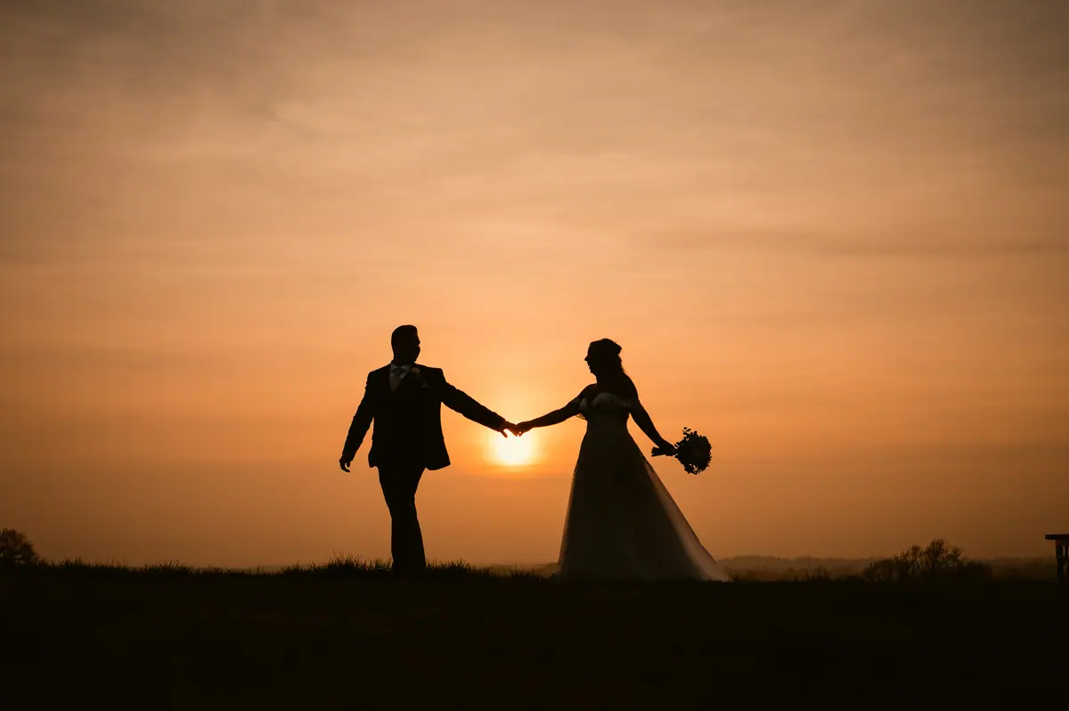 Hayley and Jayrrd holding hands in silhouette beneath orange skies