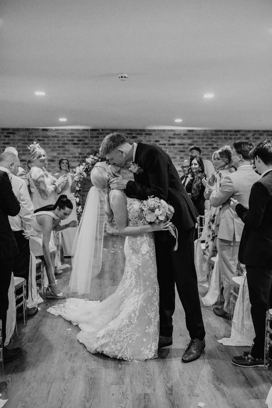 Jack and Harriet kissing beneath white drapes during their indoor ceremony