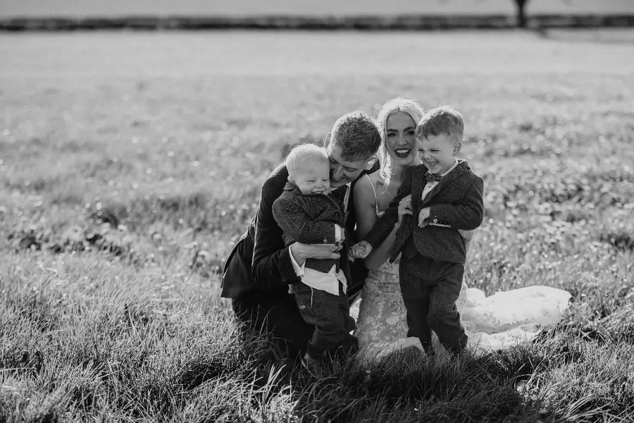 The couple crossing a field with two young boys in black and white