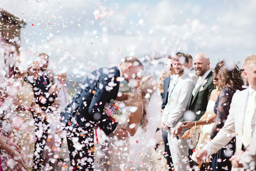 Dense confetti surrounding the couple and guests outside the barns