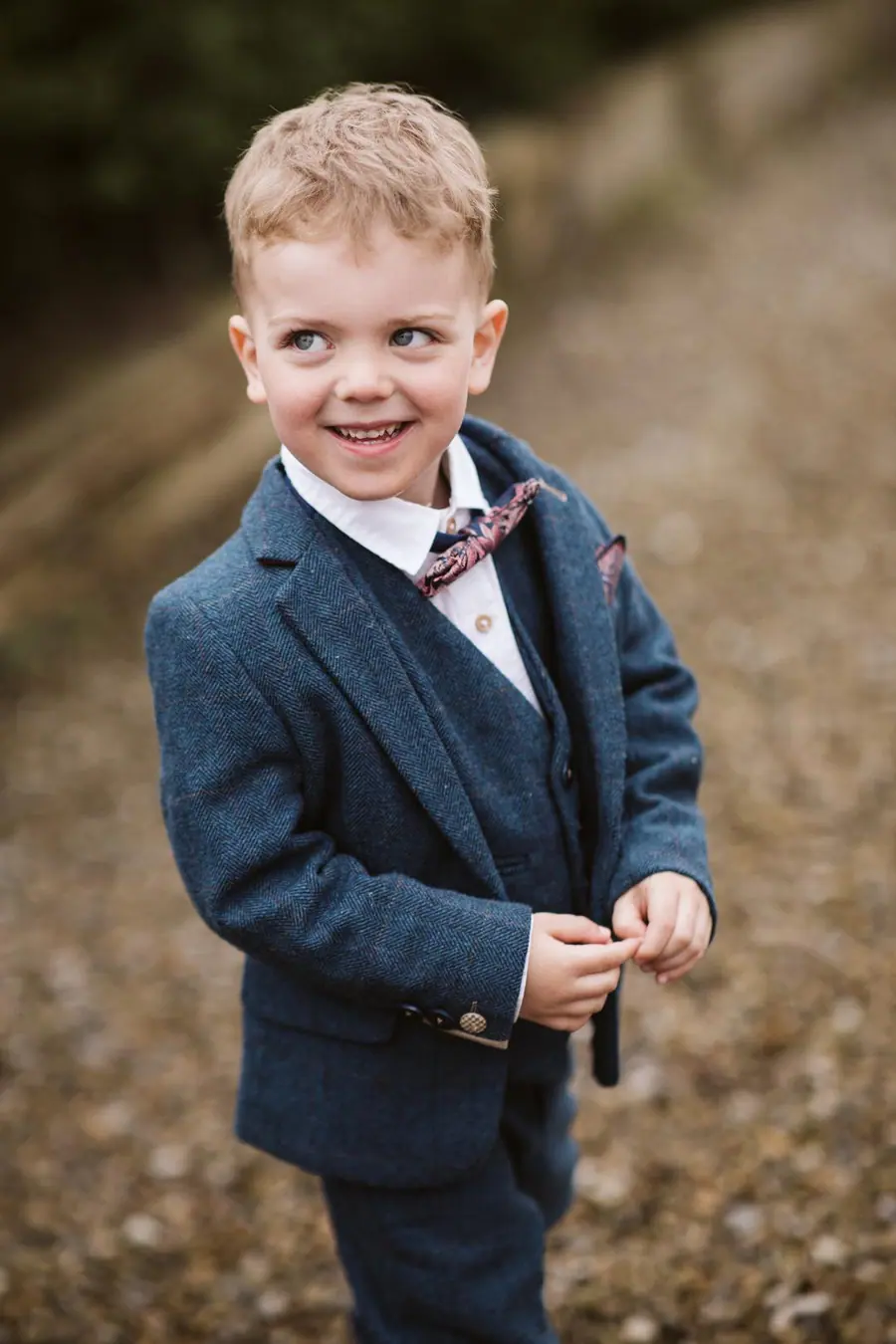 Young boy in a blue suit and patterned bow tie outdoors