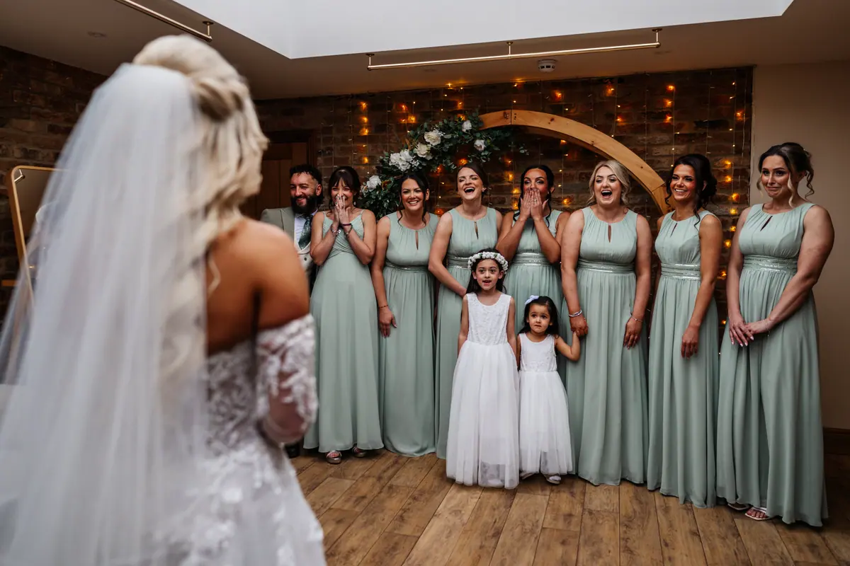 Jodie facing eight women and a young girl in pale dresses