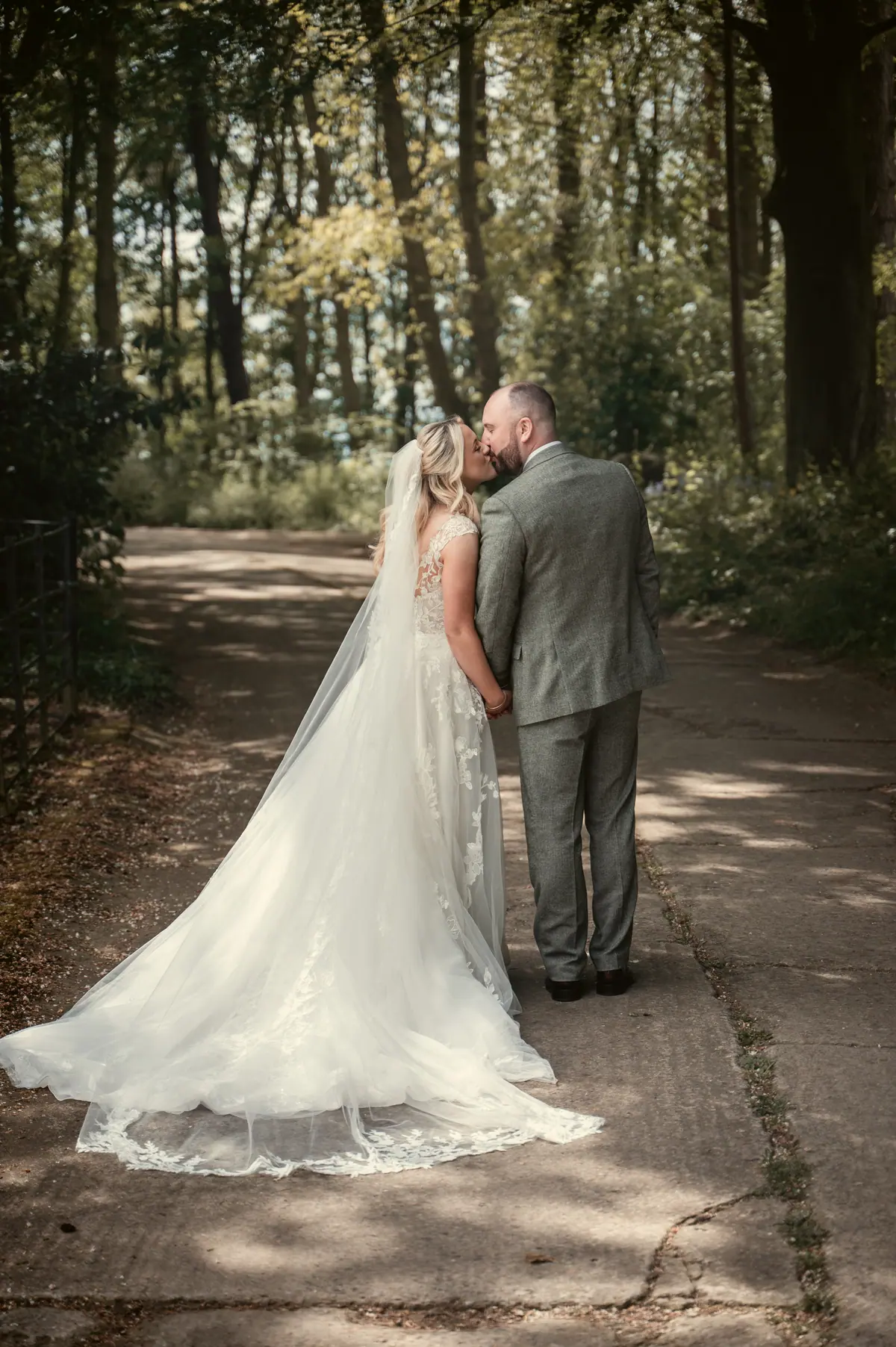 The couple standing together on a sunlit path through the woods