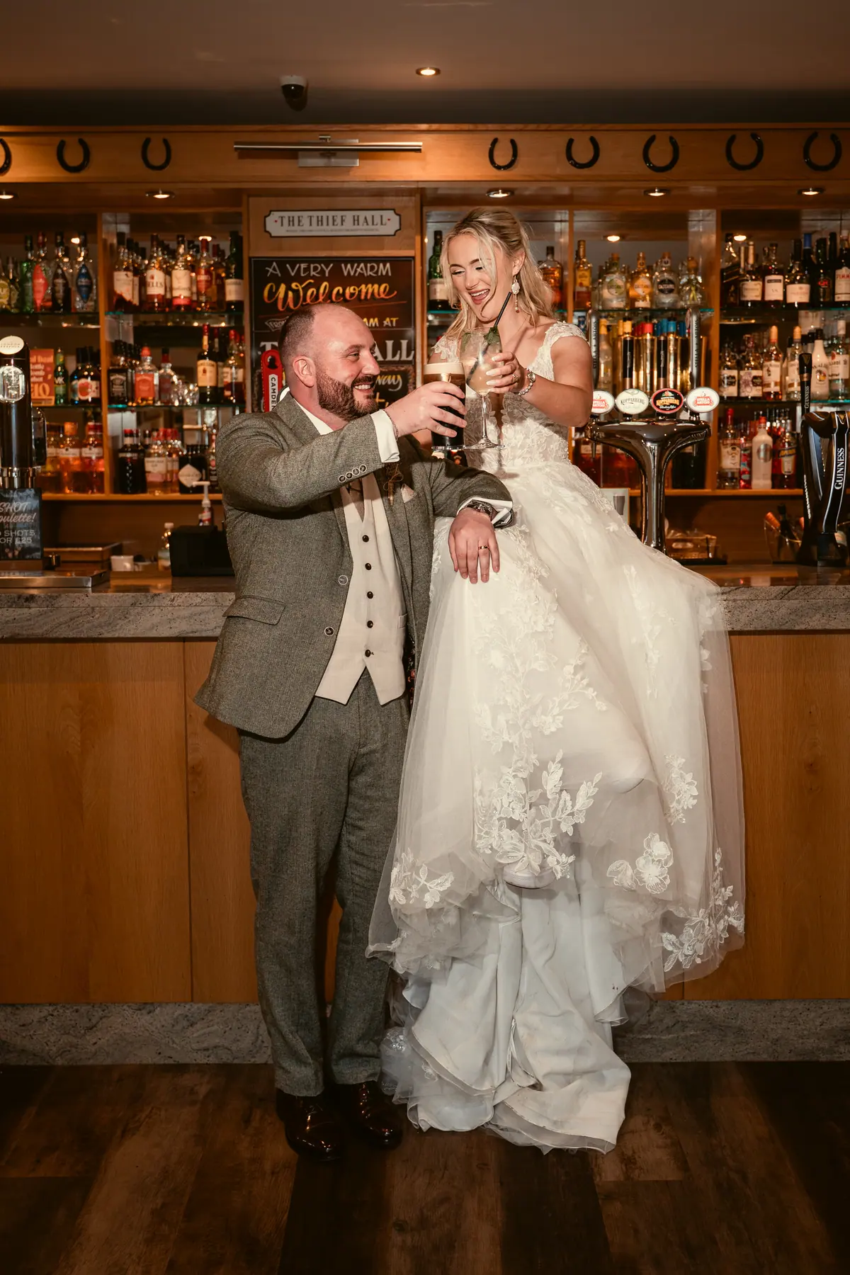 Katie and Chris standing together before the stocked Thief Hall bar