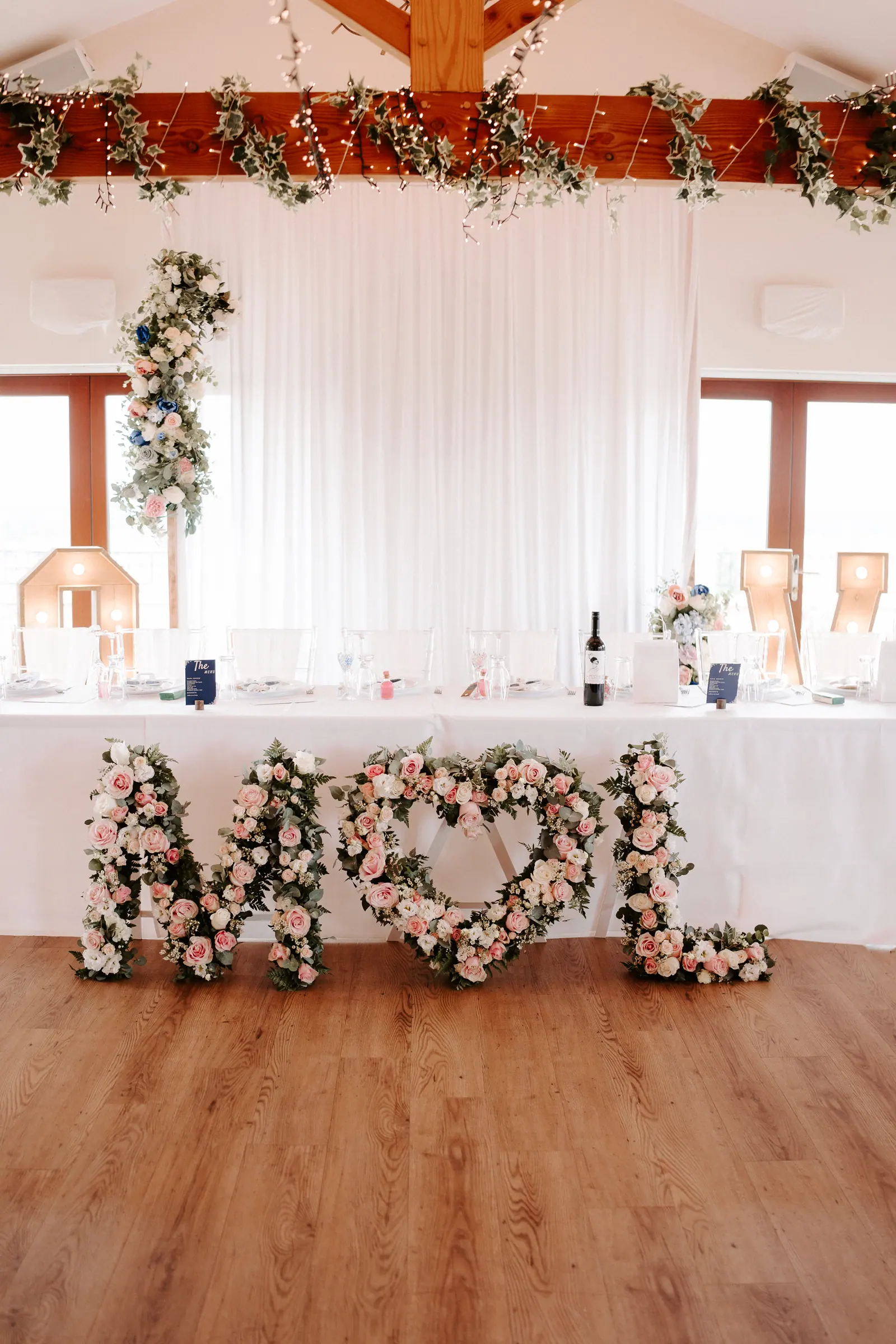 Laura and Marc's top table beneath white drapes and pink flowers