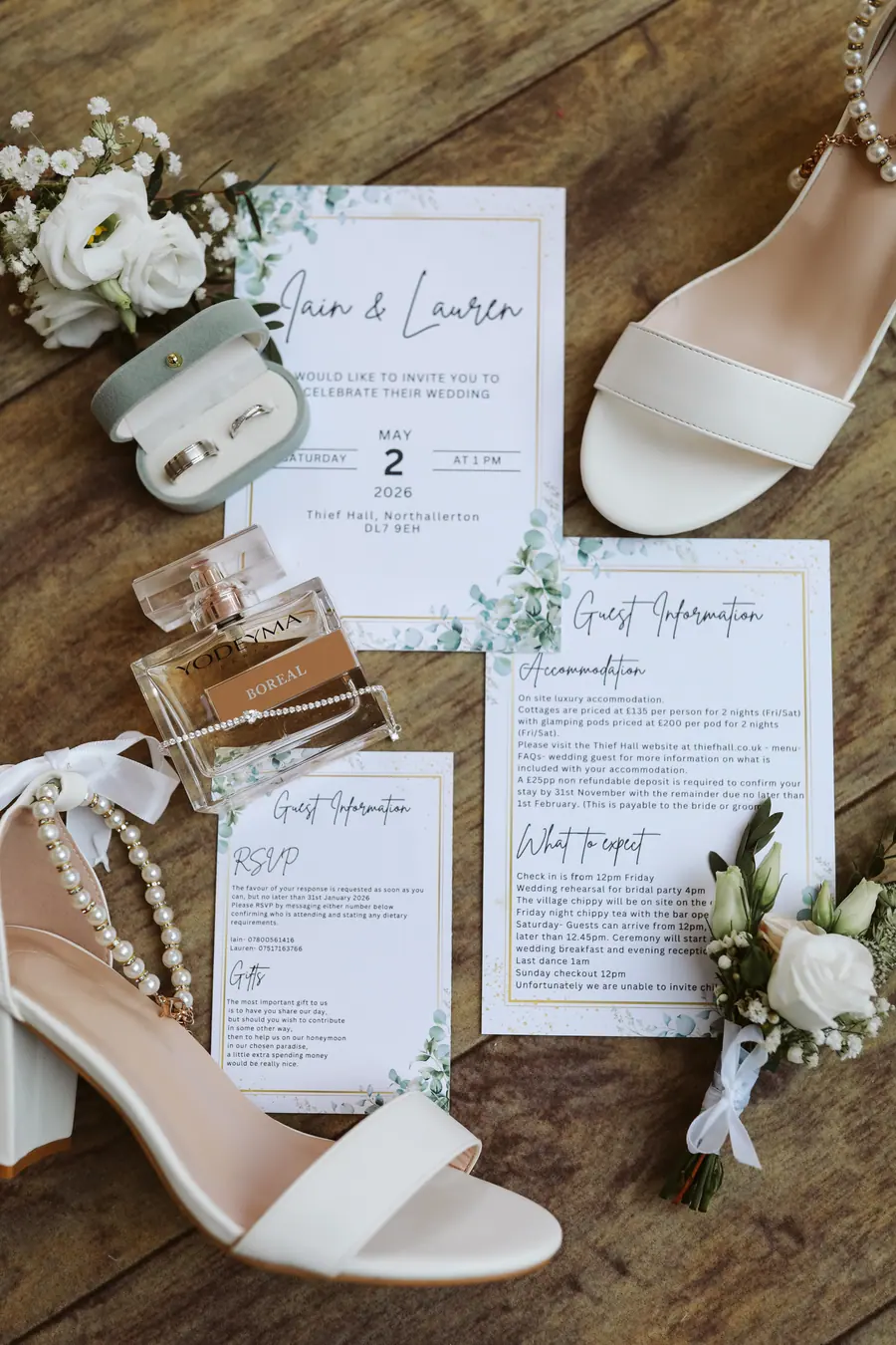White shoes, perfume and wedding stationery arranged on a wooden table