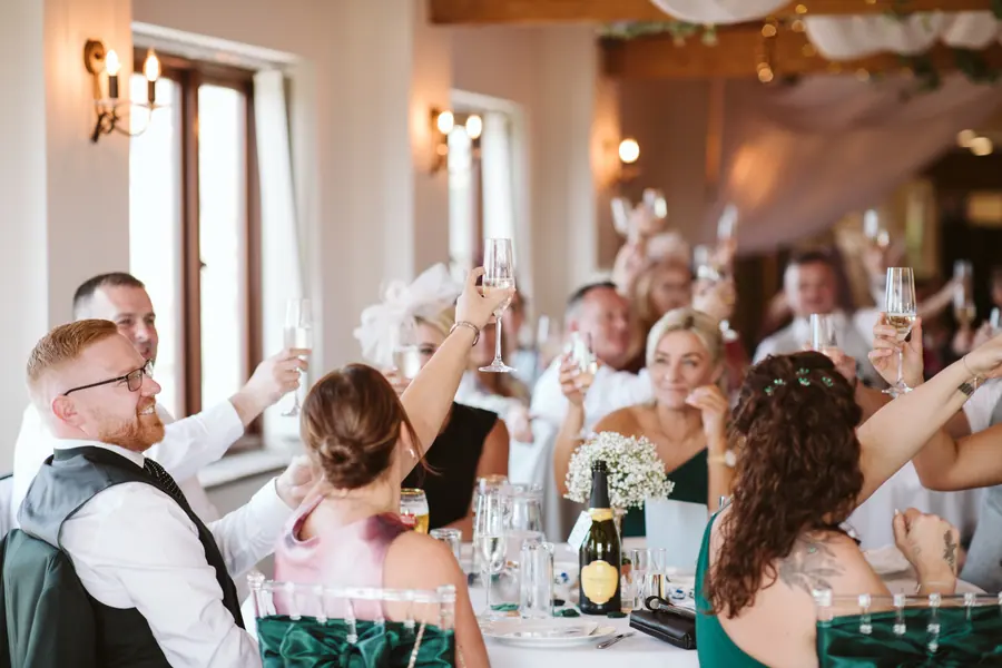 Dinner guests raising glasses around the couple inside the Hall