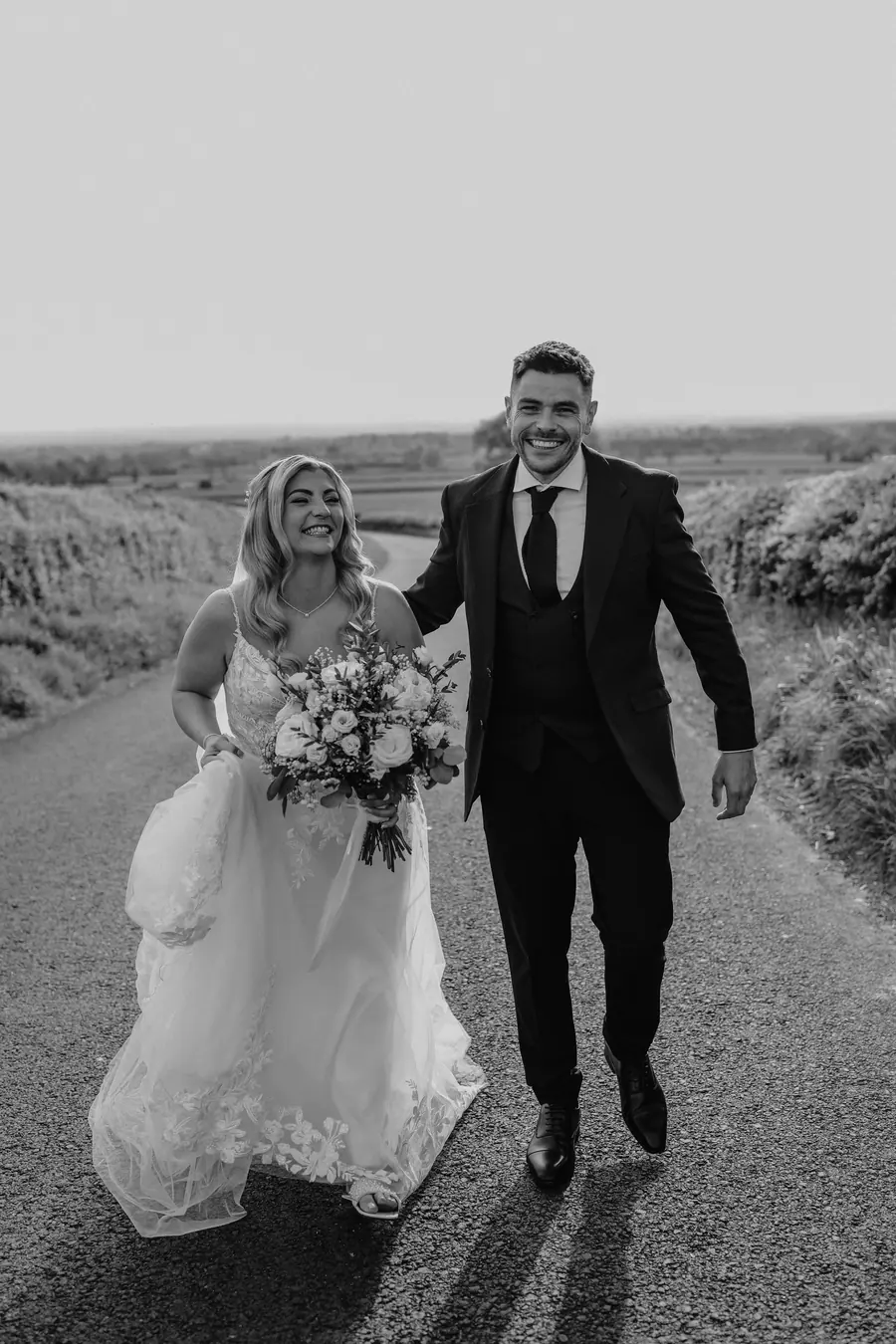 Lauren and Iain walking together along the lane in black and white