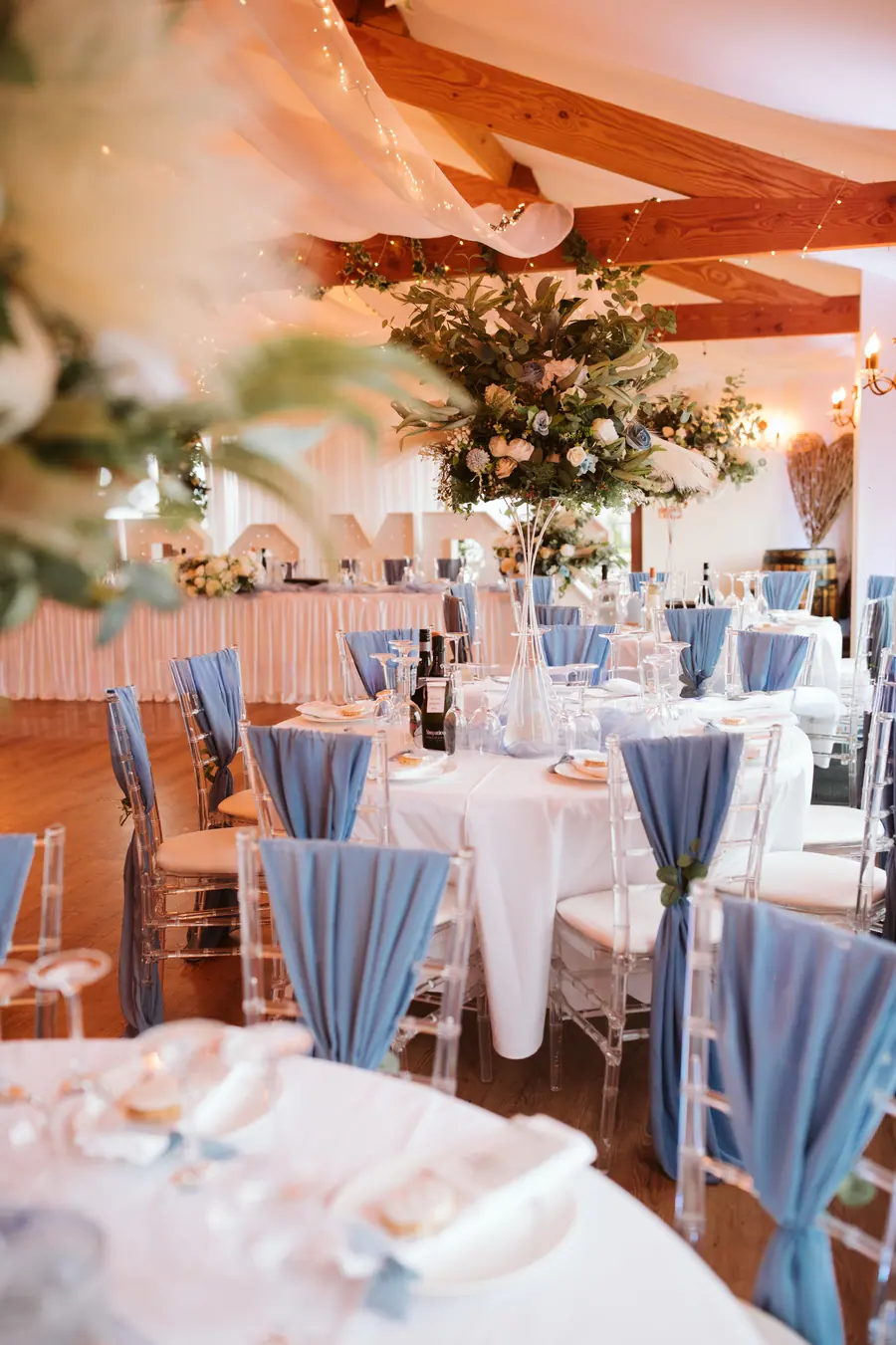 Round Hall tables dressed with pale blue napkins and tall greenery