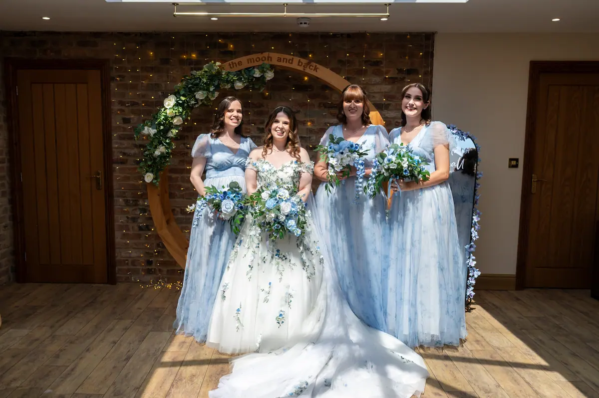 Megan standing with four women carrying blue and white bouquets