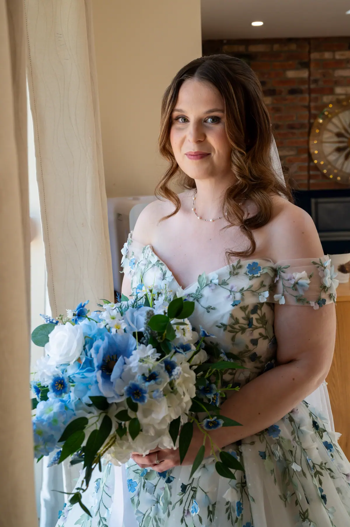 Woman in pale blue holding a blue and white bouquet indoors