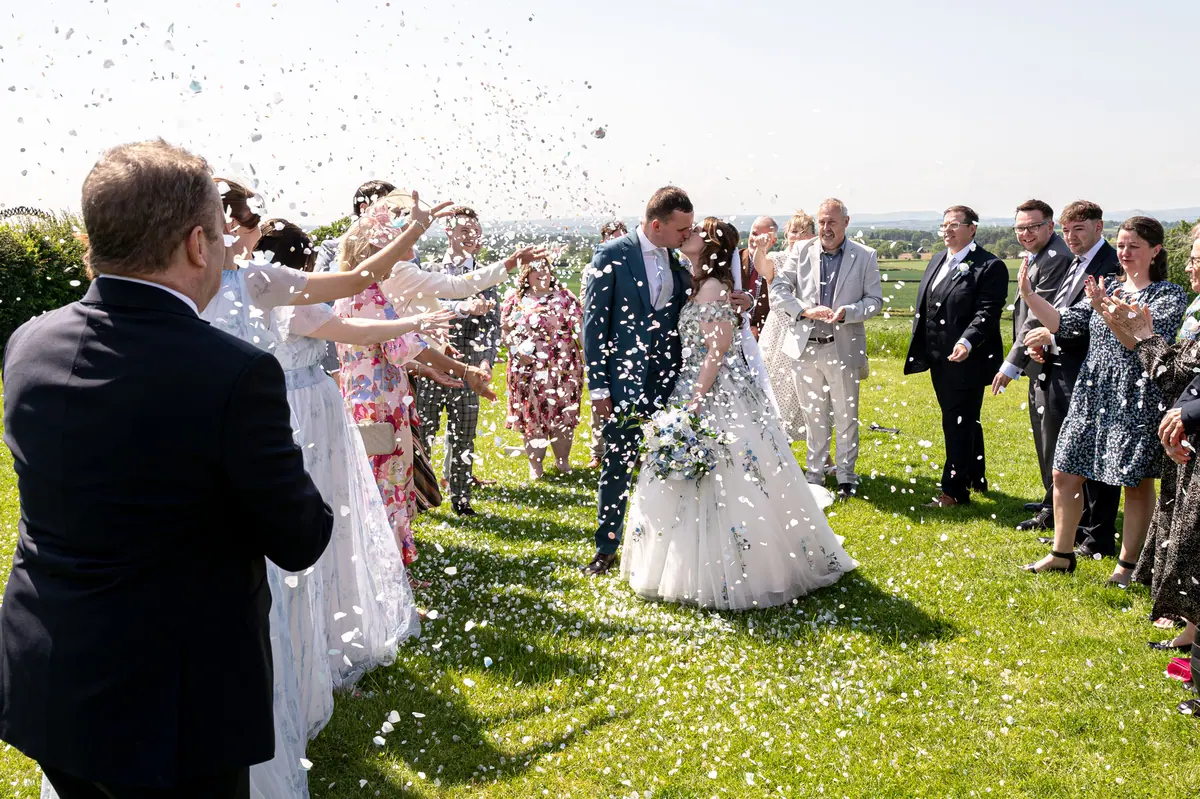 Megan and Dan walking through dense confetti between two guest lines