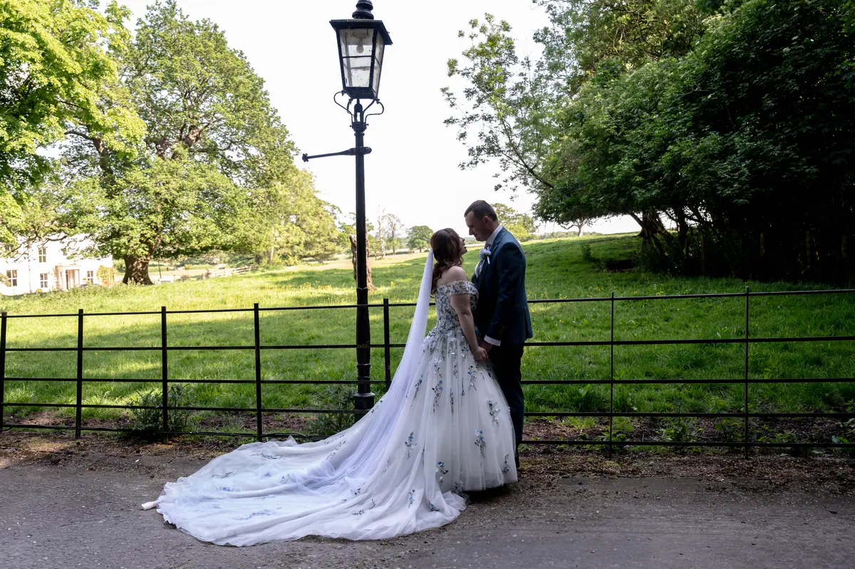 Megan and Dan beside an iron fence with green fields behind