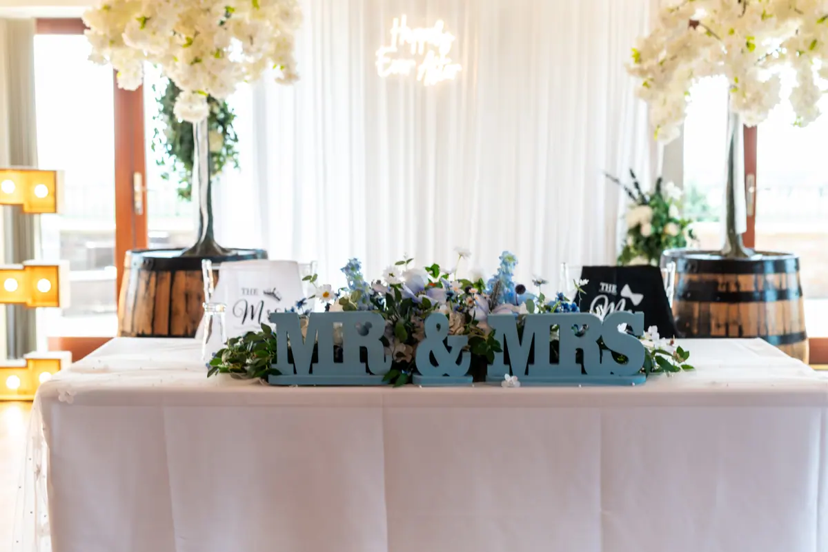 White top table with flowers, barrels and dark green name letters