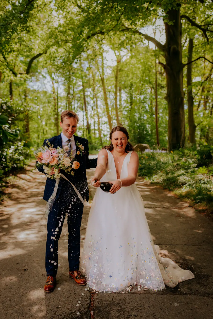 The couple holding confetti cones while walking together through the trees