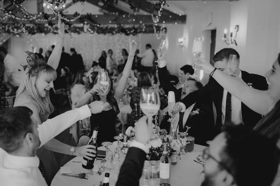 Guests raising glasses together around a table in black and white