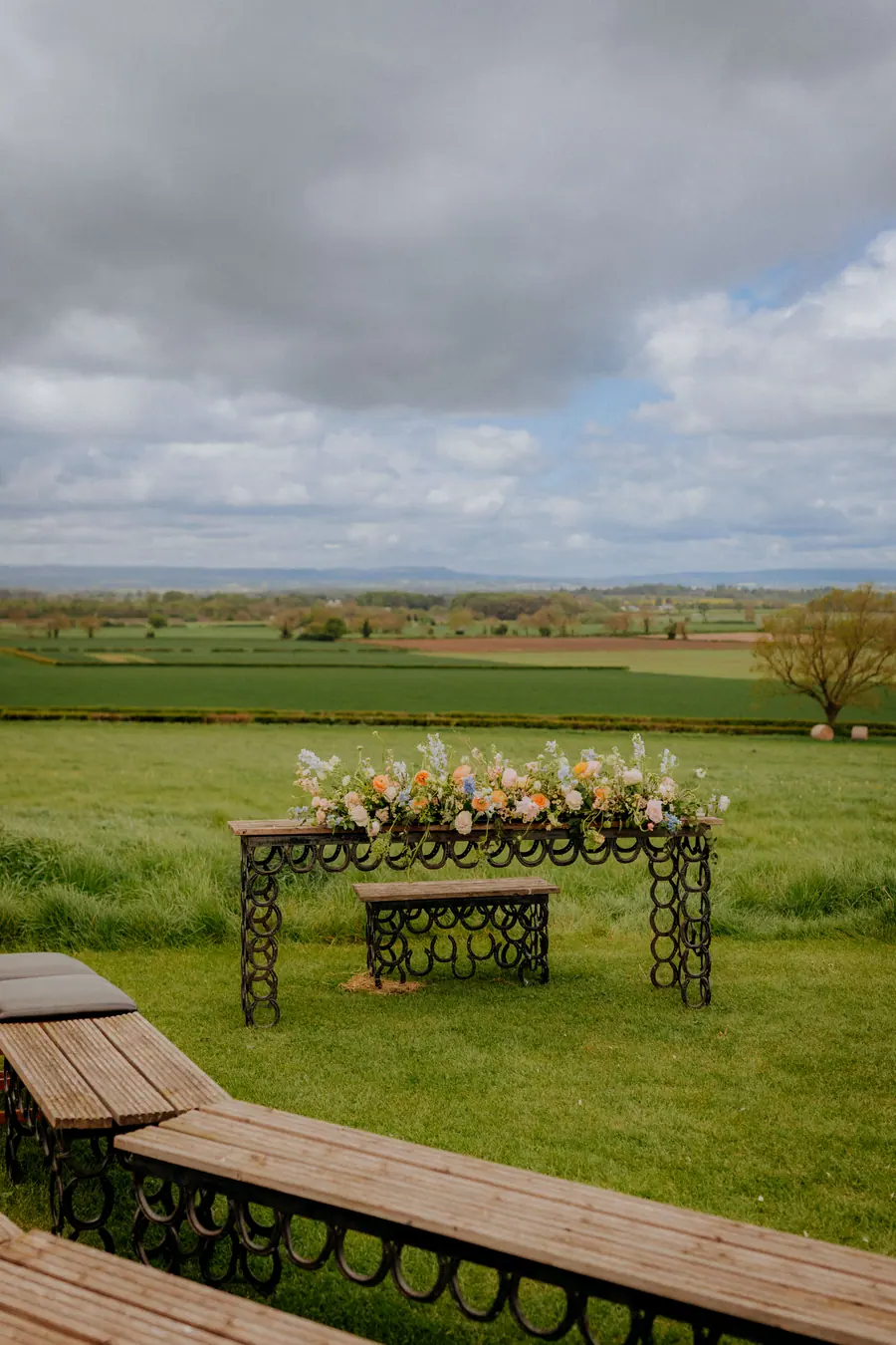 Empty iron bench looking across the fields beneath a cloudy sky