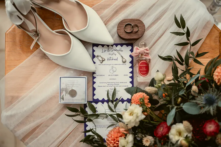 Shoes, rings, perfume and rust flowers arranged around purple stationery