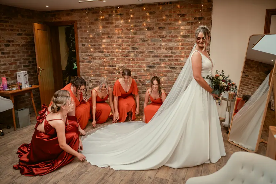 Olivia getting ready with women wearing rust, red and orange dresses