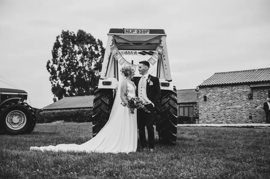Olivia and Granville standing together beneath the raised front of a tractor