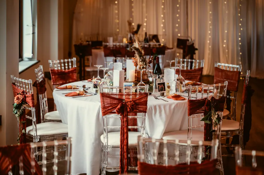 Round dinner tables dressed with rust chairs and warm autumn flowers