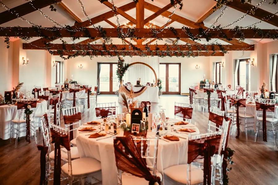 Hall dining room arranged with rust chairs beneath greenery and lights