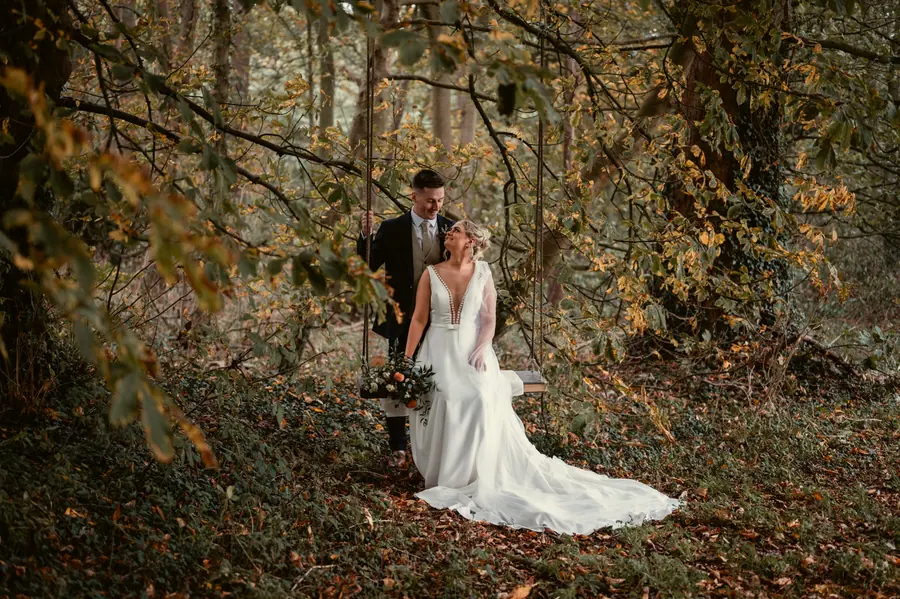 The couple walking together through woodland with turning autumn leaves