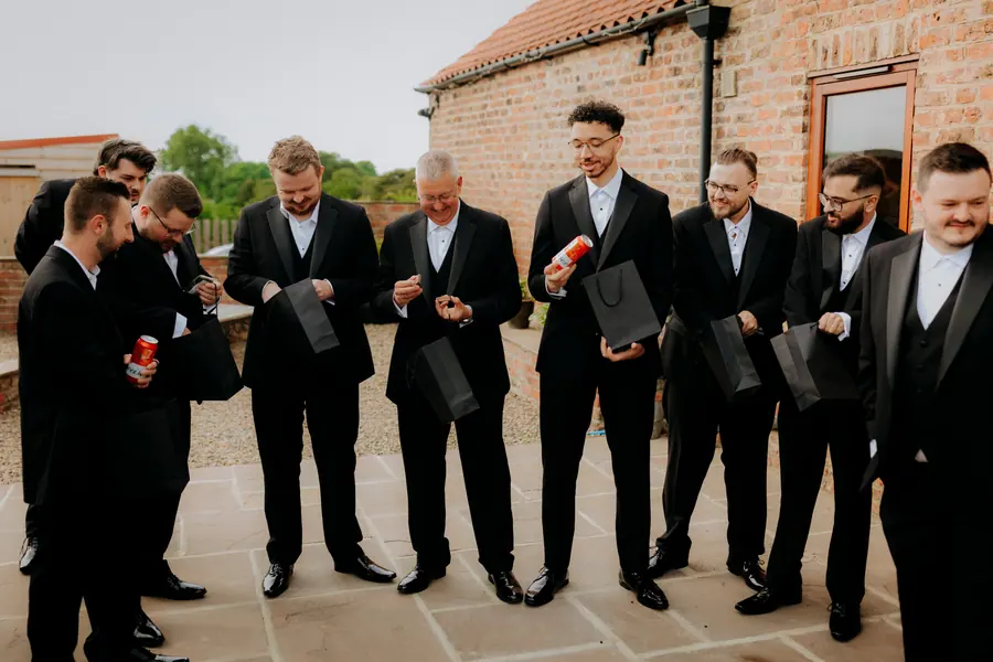 Luke and six men checking their watches outside the brick barns
