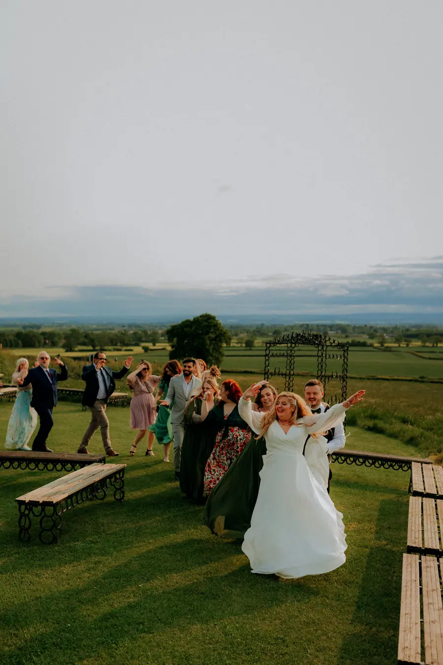 Guests gathered around Olivia on the lawn above the open fields