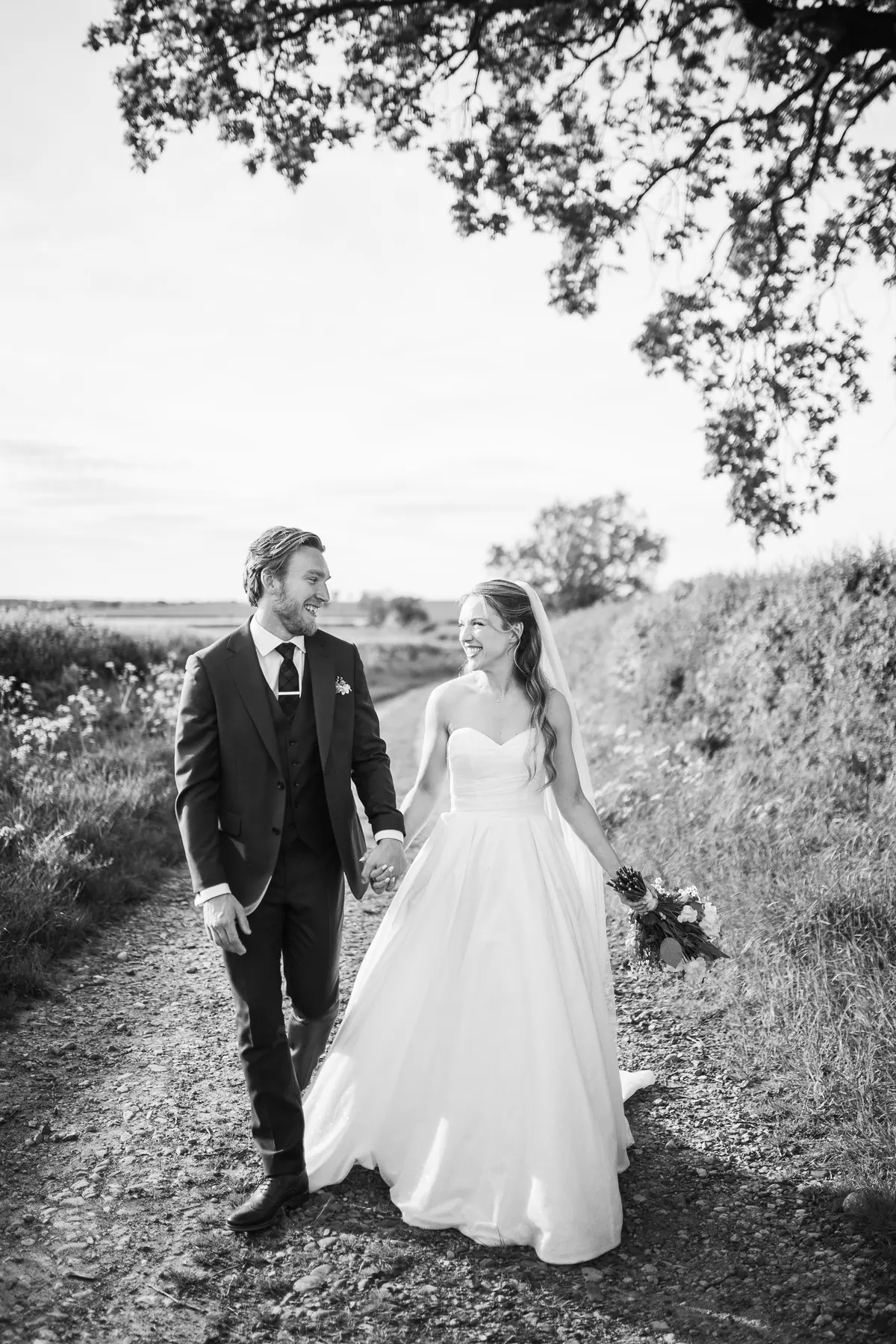 The couple walking along a field edge in black and white