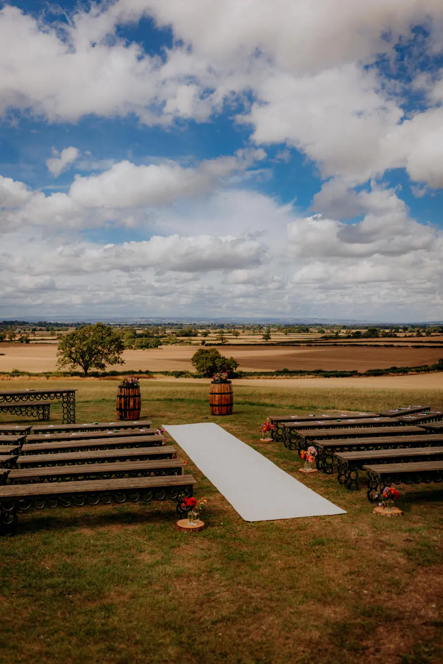 White aisle between horseshoe benches with small colourful flower arrangements