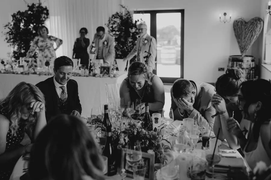 Guests gathered around the couple during speeches in black and white