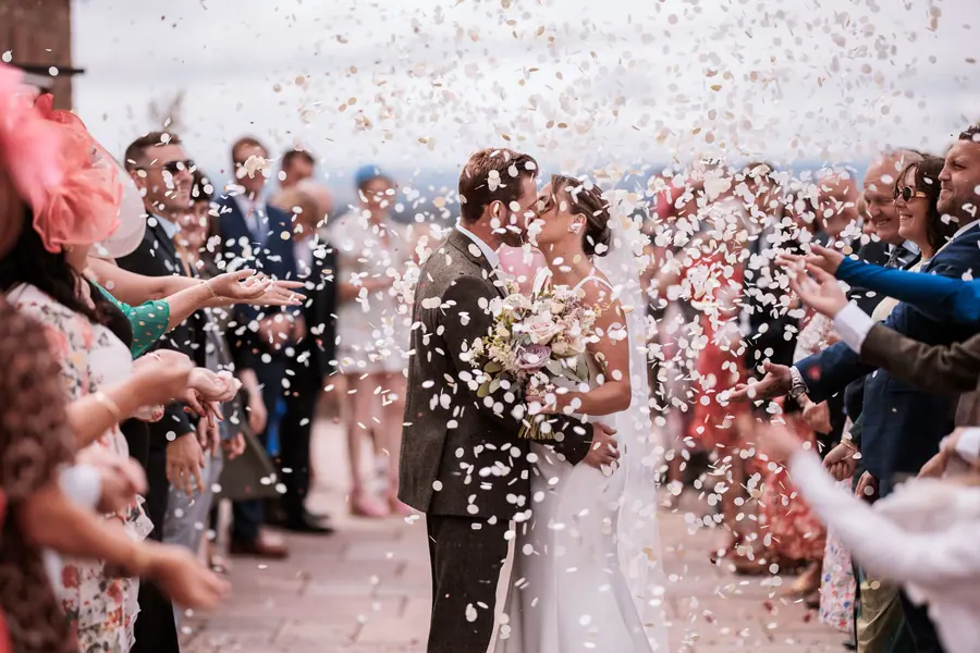 Confetti surrounding the couple between guests outside the brick barns