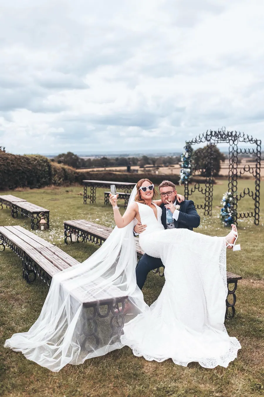 Sophie and Jake sitting on a horseshoe bench in heart-shaped sunglasses