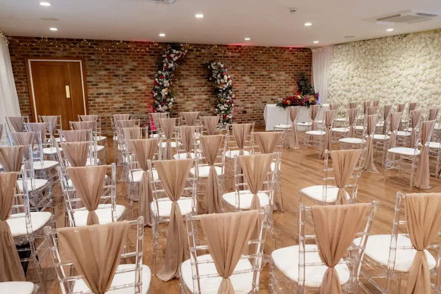 Indoor ceremony aisle leading towards red, pink and white flower arrangements