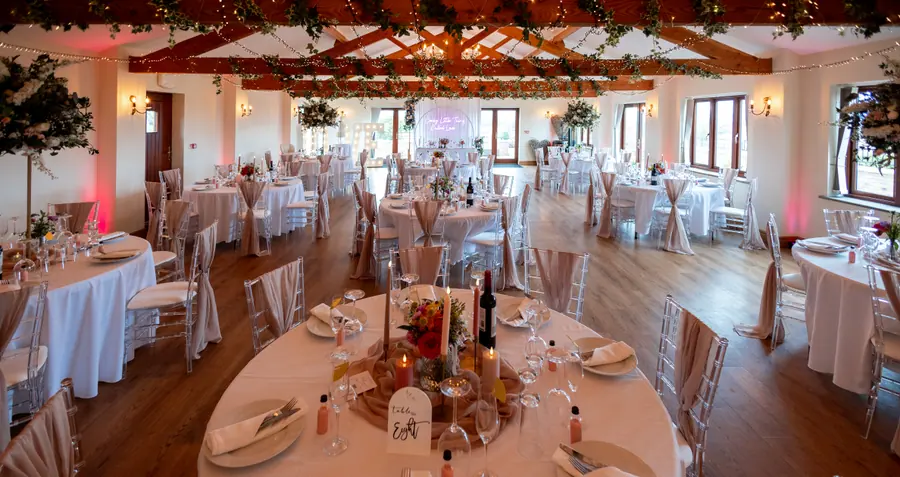 Hall dining room arranged with round tables and tall floral centrepieces