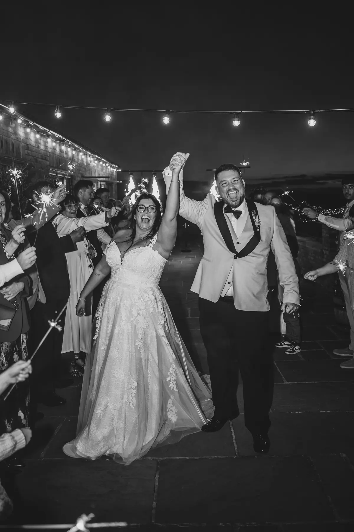 The couple raising their arms on the dance floor in monochrome