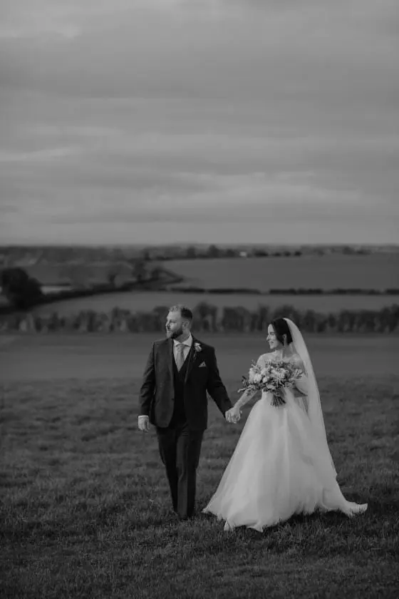 Zoe and Scott walking hand in hand across a dark late-autumn field