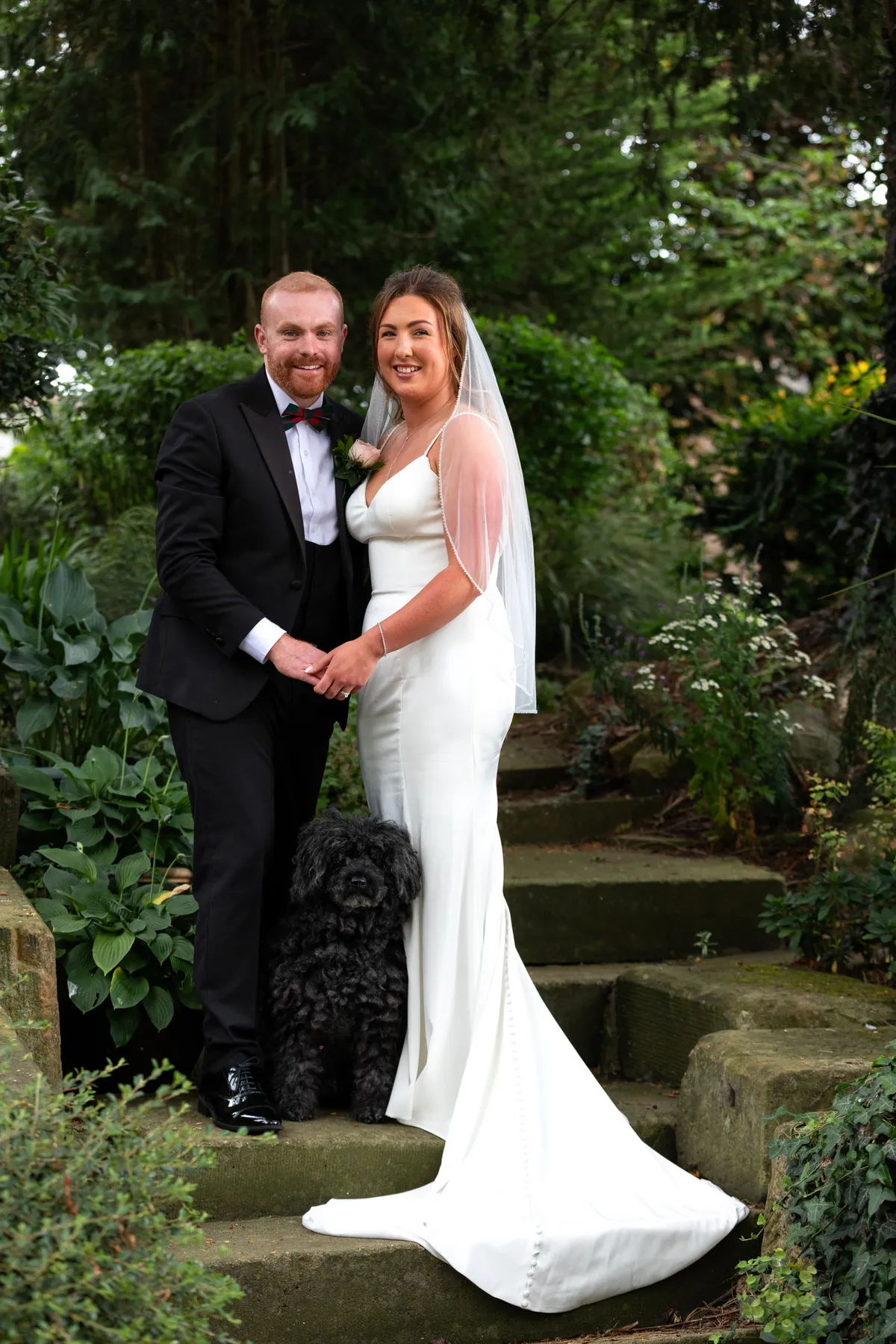 Gabi and Marcus with their dog on garden steps on their wedding day