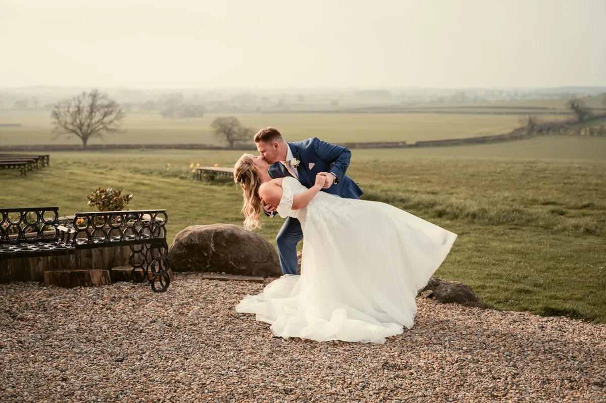 Hayley and Jayrrd sharing a kiss overlooking the countryside on their wedding day