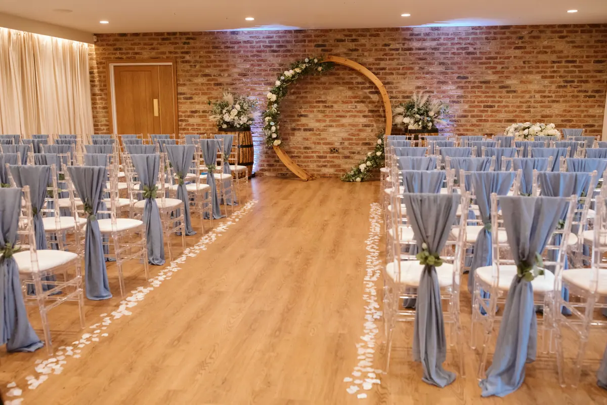 Petal-lined indoor ceremony aisle leading to a circular floral backdrop