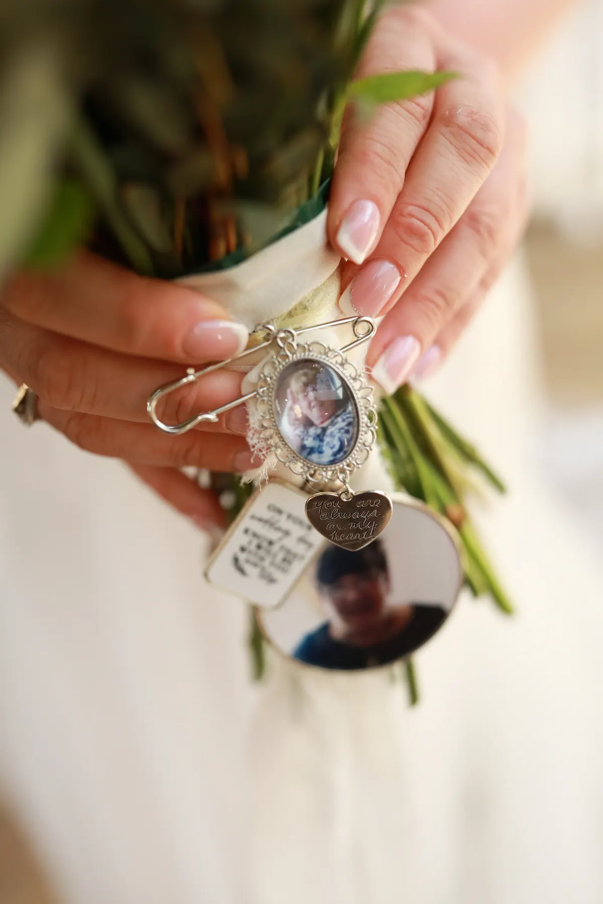 A wedding bouquet with a small memorial locket tied among the flowers
