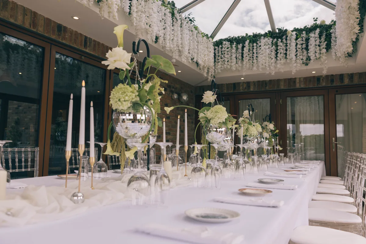 The Orangery dressed with white flowers and mirrored vases beneath its glazed roof