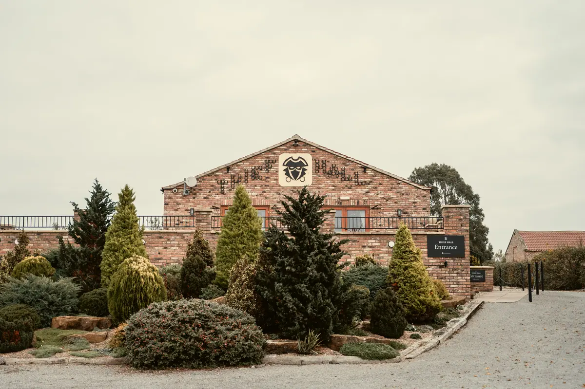 Brick entrance building and planted grounds beneath a pale autumn sky