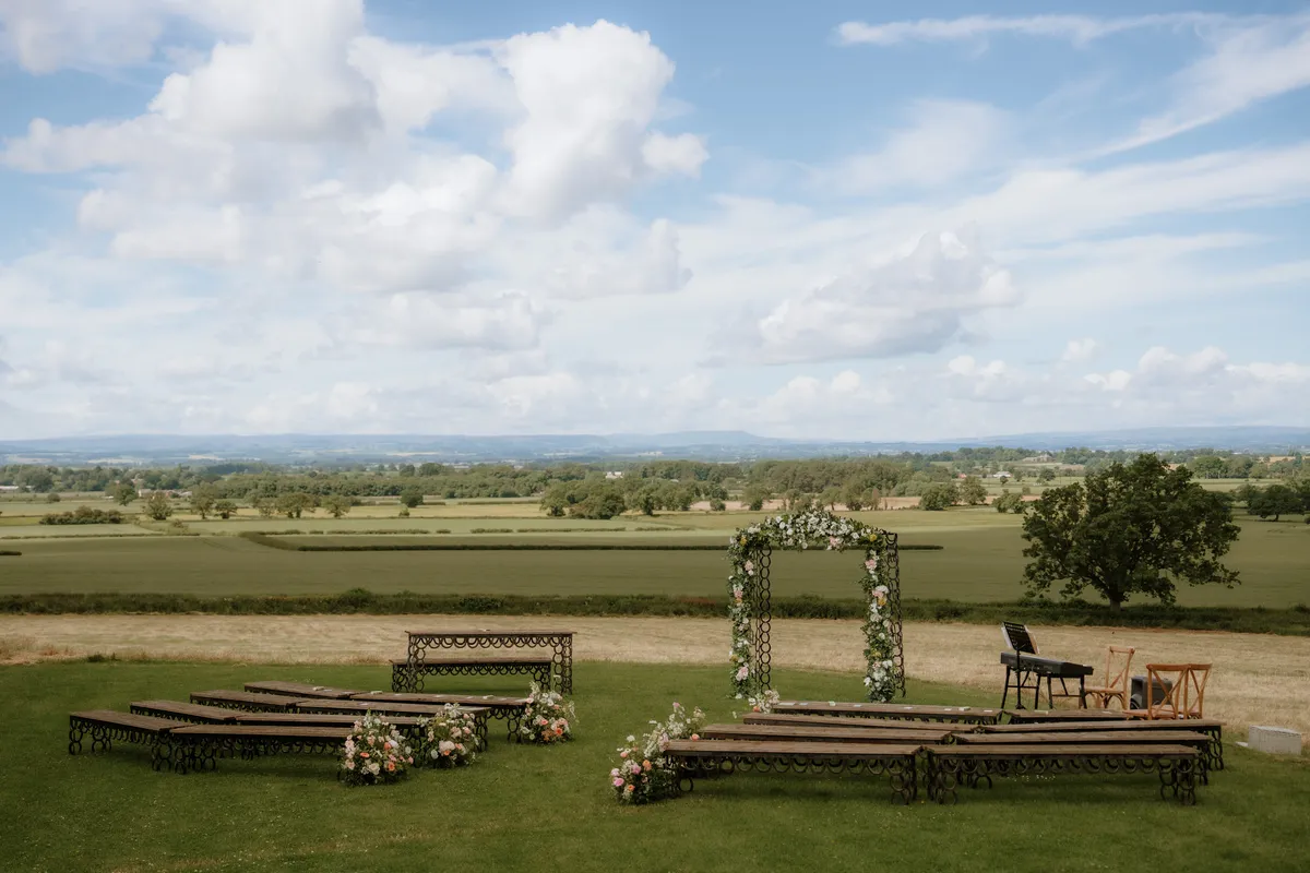 A flower-covered ceremony arch and benches overlooking the North Yorkshire countryside at Thief Hall