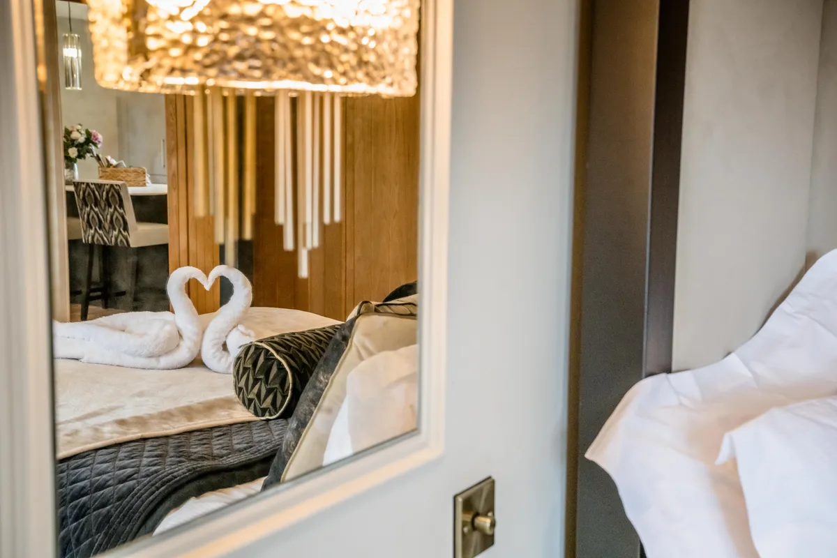 Towel swans on the bridal-suite bed reflected in a mirror at Bateman Byre