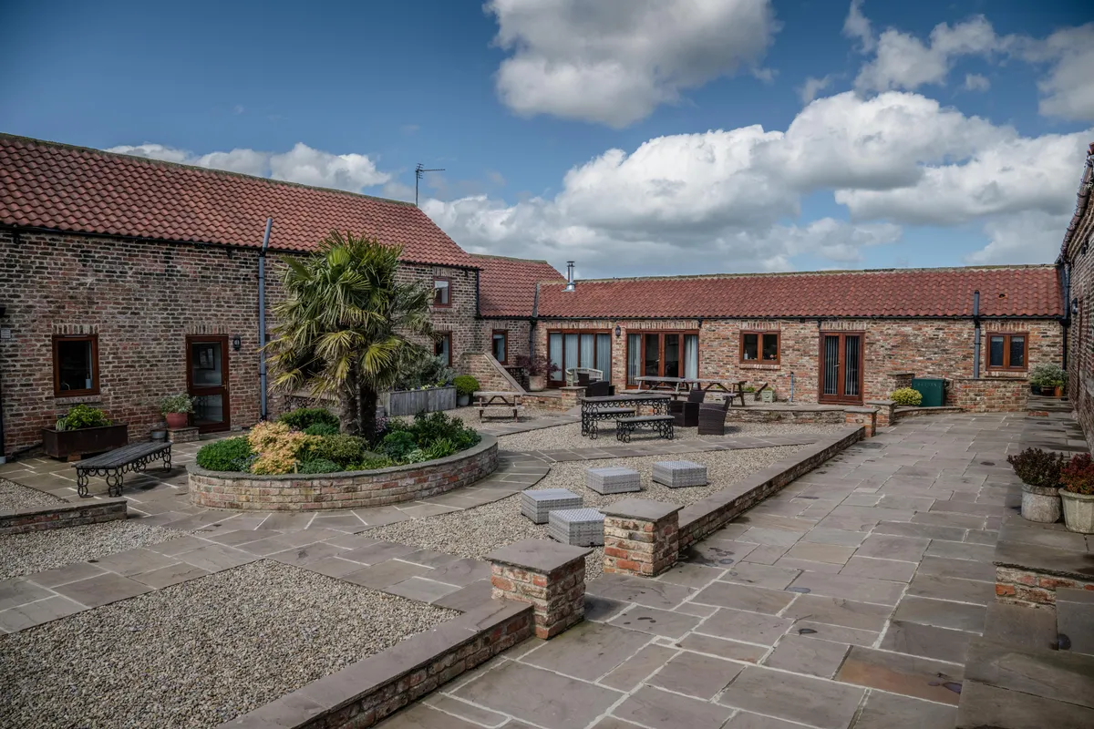 The finished courtyard at Thief Hall, with brick cottages, planting and outdoor seating